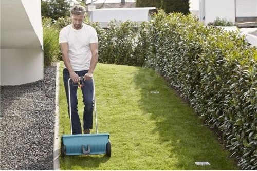 Sypací vozík rovnoměrně rozptýlí hnojivo po trávníku
